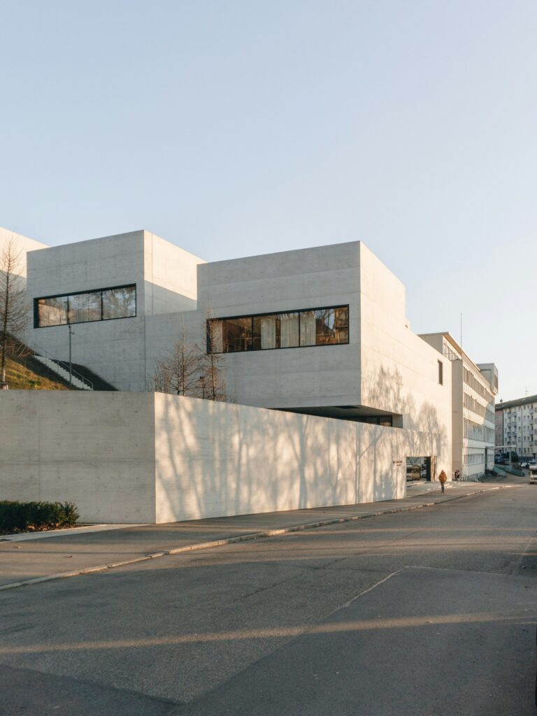 Heller geometrischer Baukörper zwischen Bäumen